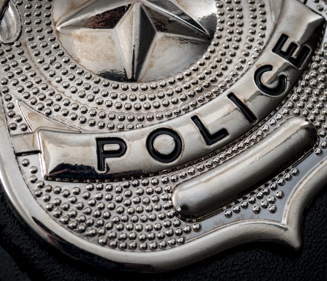 Silver police badge close-up on black background.
