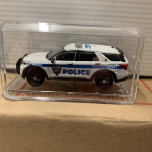 A miniature white police SUV model in a clear display case.