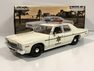 A vintage white police car model with a sheriff's star and red-blue lights.